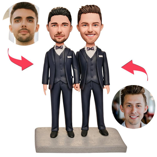 Angled close-up of personalised male same-gender couple bobbleheads showing engraved text on the base and sculpted facial detail — bespoke polymer clay keepsake