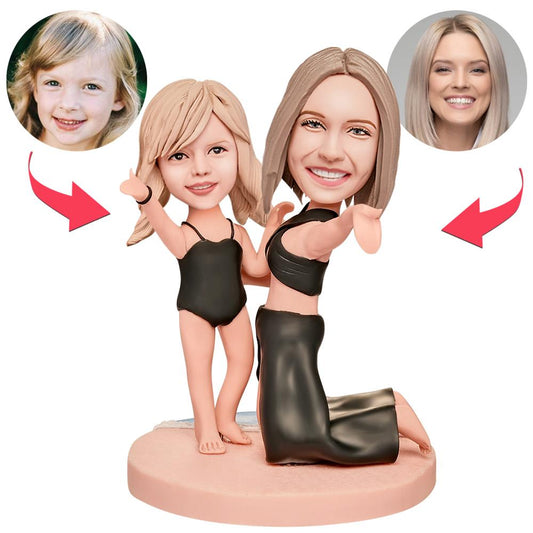 Personalised mother and daughter polymer clay bobblehead in swimsuits, close-up of customised heads and engraved text on the base — bespoke swimsuit bobblehead keepsake