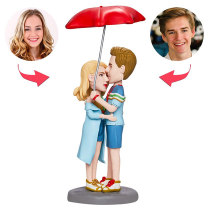 Personalised Valentine’s bobblehead couple embracing under an umbrella with engraved base, polymer clay custom bobblehead ideal as a romantic gift or anniversary keepsake