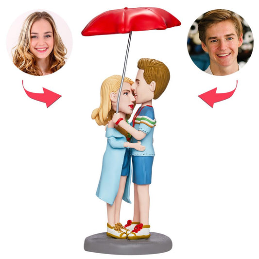 Personalised Valentine’s bobblehead couple embracing under an umbrella with engraved base, polymer clay custom bobblehead ideal as a romantic gift or anniversary keepsake