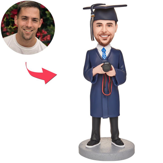 Personalised graduation bobblehead of a boy holding a camera with engraved text on the base, polymer clay custom head matched to your photo — perfect photography graduate gift