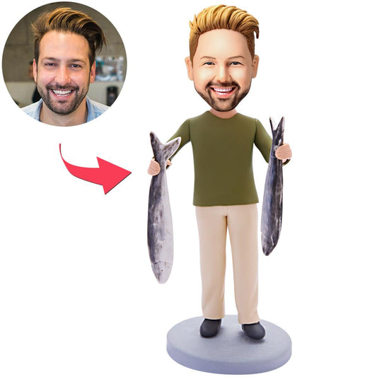 Personalised bobblehead in polymer clay of a man carrying two small fish, a custom bobblehead with engraved text on the base — ideal fishing bobblehead gift.