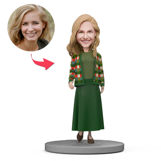 Personalised polymer clay bobblehead in a green skirt suit, full-body front view on an engraved base — custom bobble head for UK and Australia