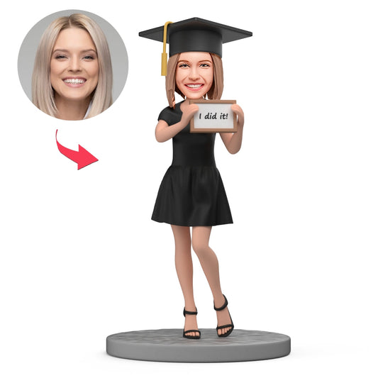 Personalised polymer clay 'I Did It!' graduation bobblehead of a female graduate in cap, gown and stole — custom head likeness, ideal personalised graduation gift keepsake