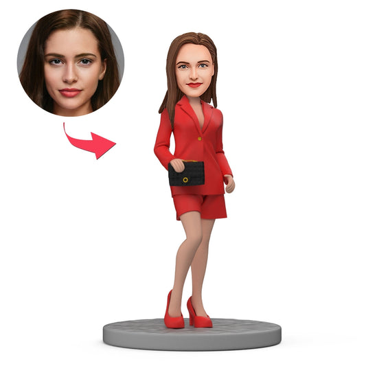 Custom bobblehead of a stylish female boss in a red suit holding a handbag — personalised polymer clay figure with a customised head, perfect personalised boss gift