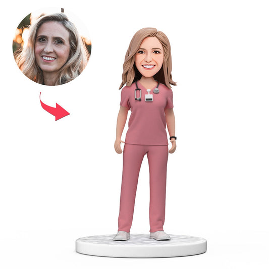 Personalised female doctor bobblehead in pink scrubs, handcrafted polymer clay with engraved base — custom head likeness, perfect NHS GP or medical graduate gift