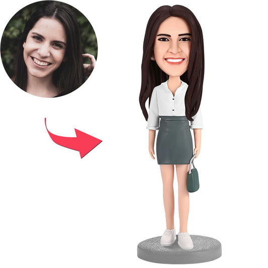 Personalised woman with bag bobblehead in polymer clay, front view showing customised head likeness and engraved personalised text on the base