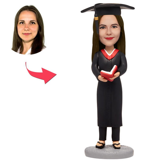 Personalised female graduate bobblehead holding a red book with engraved base — custom head polymer clay graduate keepsake
