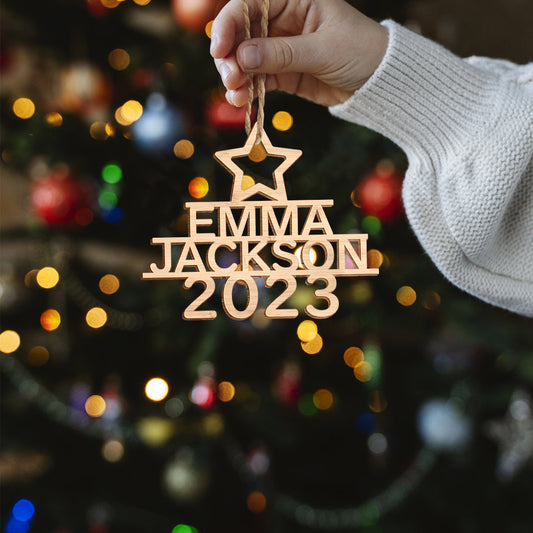 Hand-finished personalised wooden Christmas tree ornament hanging on a fir branch, bespoke custom name decoration and ideal holiday gift