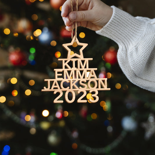 Hand-finished personalised wooden Christmas tree ornament hanging on a fir branch, bespoke custom name decoration and ideal holiday gift