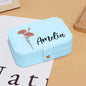 Personalised birth-flower jewellery box styled beside a handbag and passport — ideal bridesmaid, wedding or travel gift
