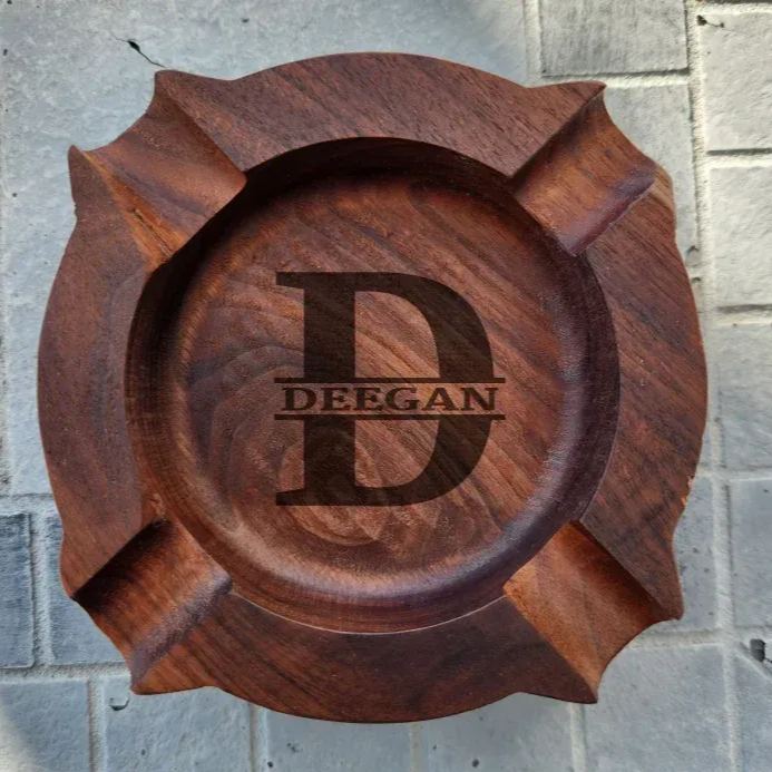 Compact personalised walnut ashtray shown in hand to illustrate size (W12cm x H2.8cm) – engraved wooden cigar rest