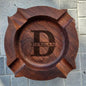 Compact personalised walnut ashtray shown in hand to illustrate size (W12cm x H2.8cm) – engraved wooden cigar rest