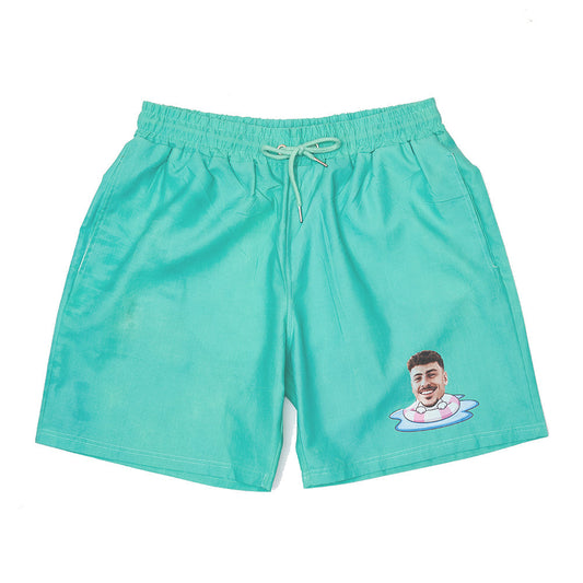 Personalised colour-changing swim trunks with customised face on green-to-blue gradient, front view – fast-drying polyester beach shorts