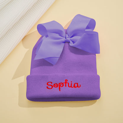 Detailed close-up of bow and stitching on personalised knit baby beanie with custom name embroidery