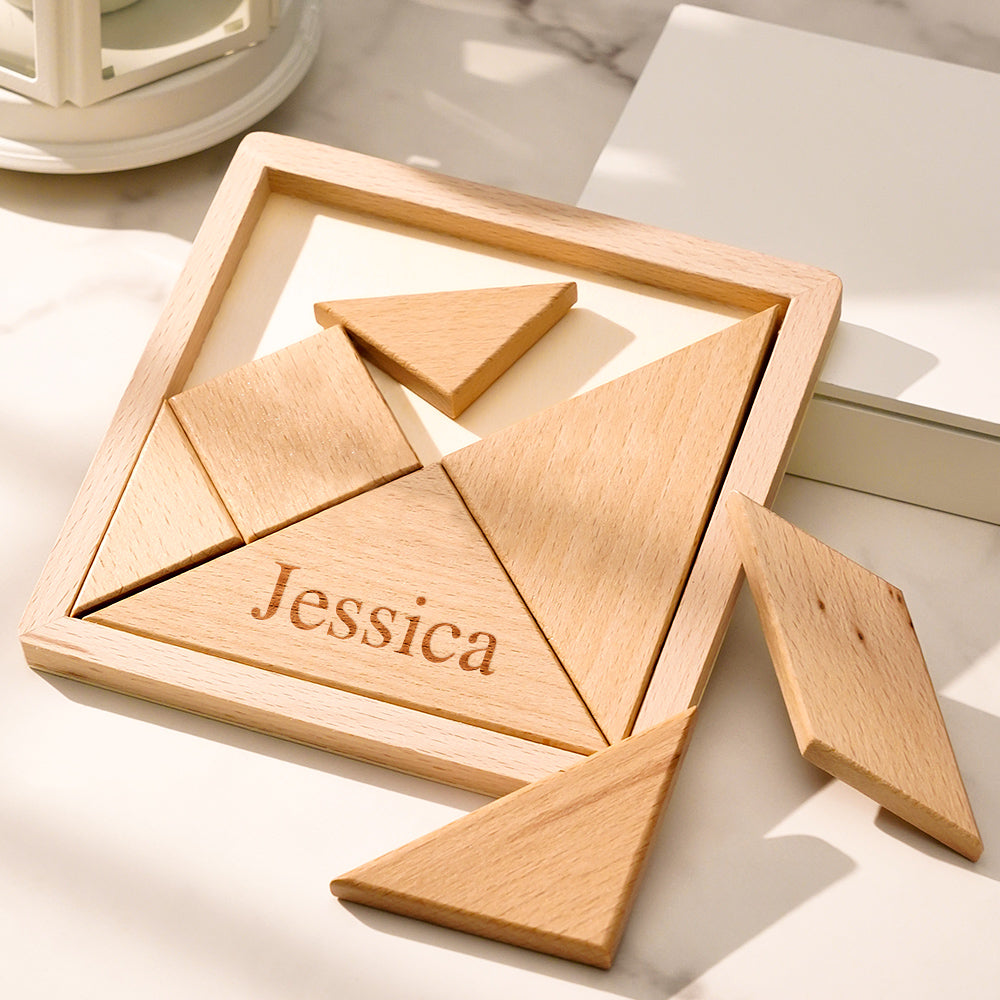 Open handcrafted wooden storage box showing the seven-piece tangram laid out in geometric shapes beside the personalised engraved lid — educational wooden jigsaw puzzle for all ages