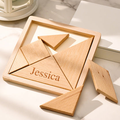 Open handcrafted wooden storage box showing the seven-piece tangram laid out in geometric shapes beside the personalised engraved lid — educational wooden jigsaw puzzle for all ages
