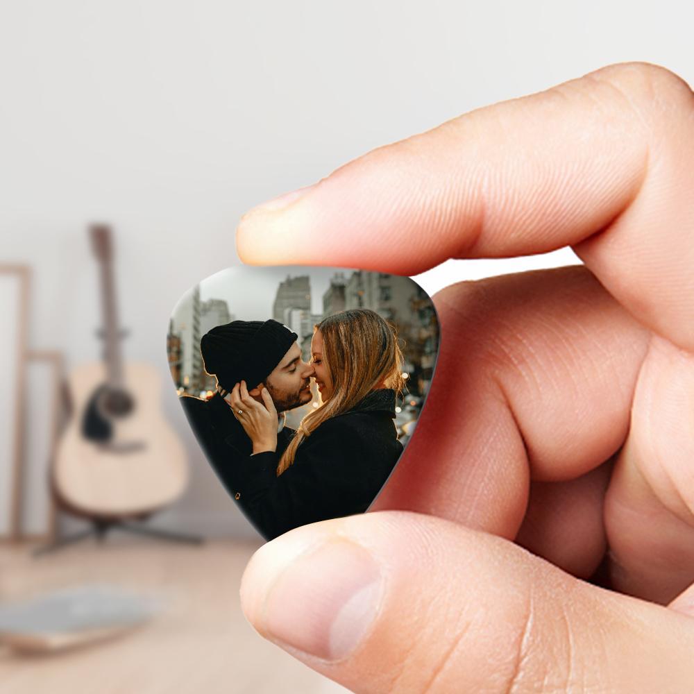 Hand holding a personalised guitar pick over acoustic guitar strings — custom photo pick in use, warm full tone from plastic pick