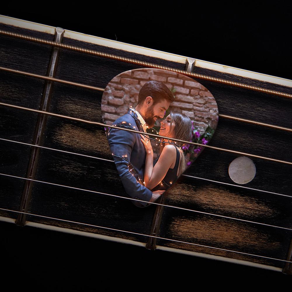 Multiple personalised guitar picks laid on a wooden surface showing varied photo and text customisations — perfect personalised gift for musicians