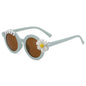Lifestyle image of a toddler wearing personalised daisy sunglasses at the beach — custom name kids sunglasses providing sun protection for outdoor play