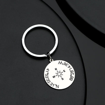 Close-up of precision engraving showing bespoke coordinates on a stainless steel keyring with integrated working compass