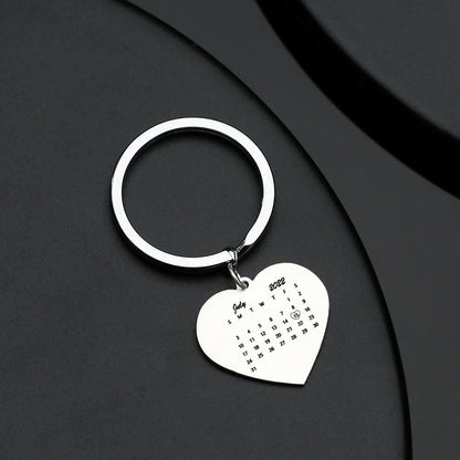 Close-up of personalised stainless steel heart keyring showing engraved calendar date and inserted photograph — a romantic anniversary keepsake