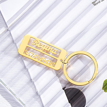 Personalised emergency contact keyring with engraved name and phone number beside keys.