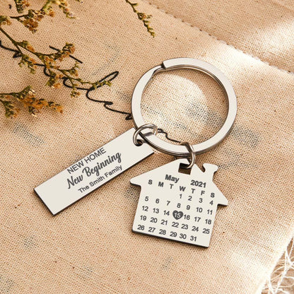 Close-up of personalised stainless steel keyring showing house and rectangular tags with precision engraving of anniversary date and name