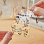 Scale view showing the acrylic keychain (5.4 × 8.6 cm) held in hand to demonstrate compact size and engraved custom text option
