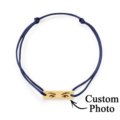 Minimalist product shot focusing on the polished stainless steel charm and delicate silk cord of personalised eyes bracelet