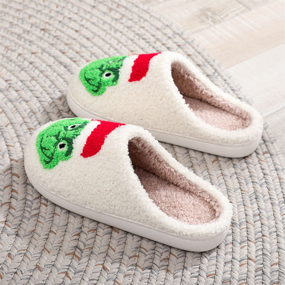 Top view of festive Grinch plush slip‑ons showing open‑mouth design and soft skin‑friendly fabric