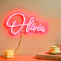 Custom personalised neon name lamp mounted above a bed creating warm ambient lighting — LED neon sign for bedroom décor