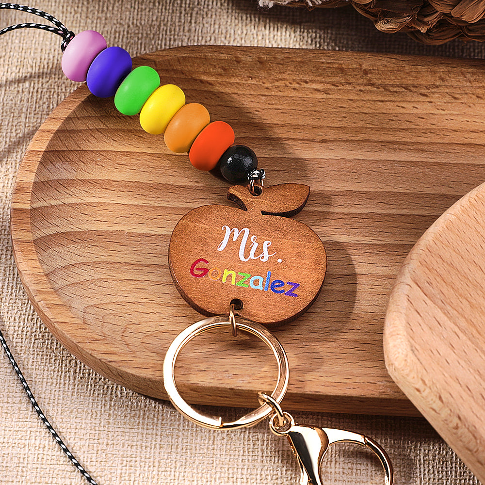 Close-up of personalised wooden apple charm showing fine grain and custom name engraving — teacher appreciation gift