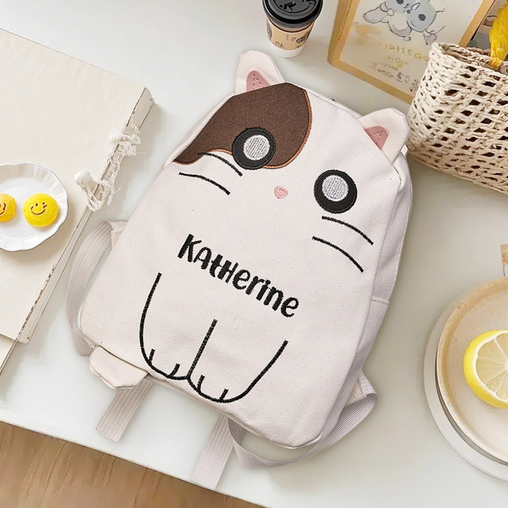 Close-up of embroidered name and playful cat motif on canvas — personalised embroidery detail for a bespoke children's backpack