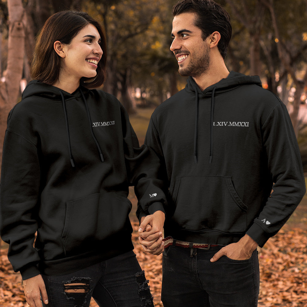 Matching couples hoodies laid flat — custom embroidered Roman numeral date, perfect anniversary present