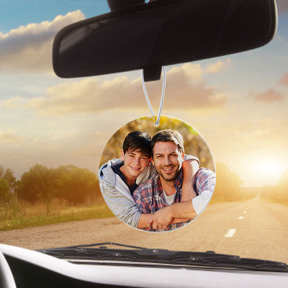 Round personalised car air freshener with a custom photo printed on premium felt, hanging from a rear-view mirror cord.