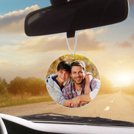Round personalised car air freshener with a custom photo printed on premium felt, hanging from a rear-view mirror cord.