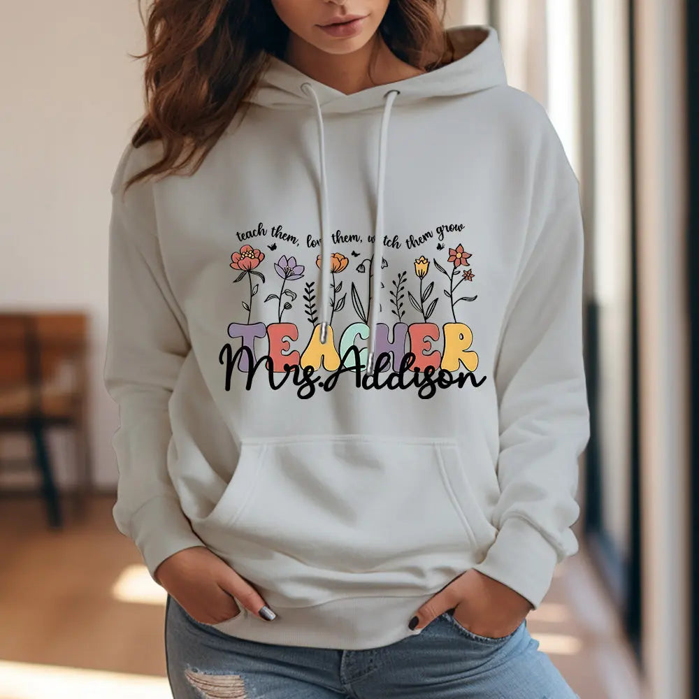 Flat-lay product image of the personalised wildflower hooded sweatshirt with custom name on the back — ideal personalised gift for teachers and colleagues