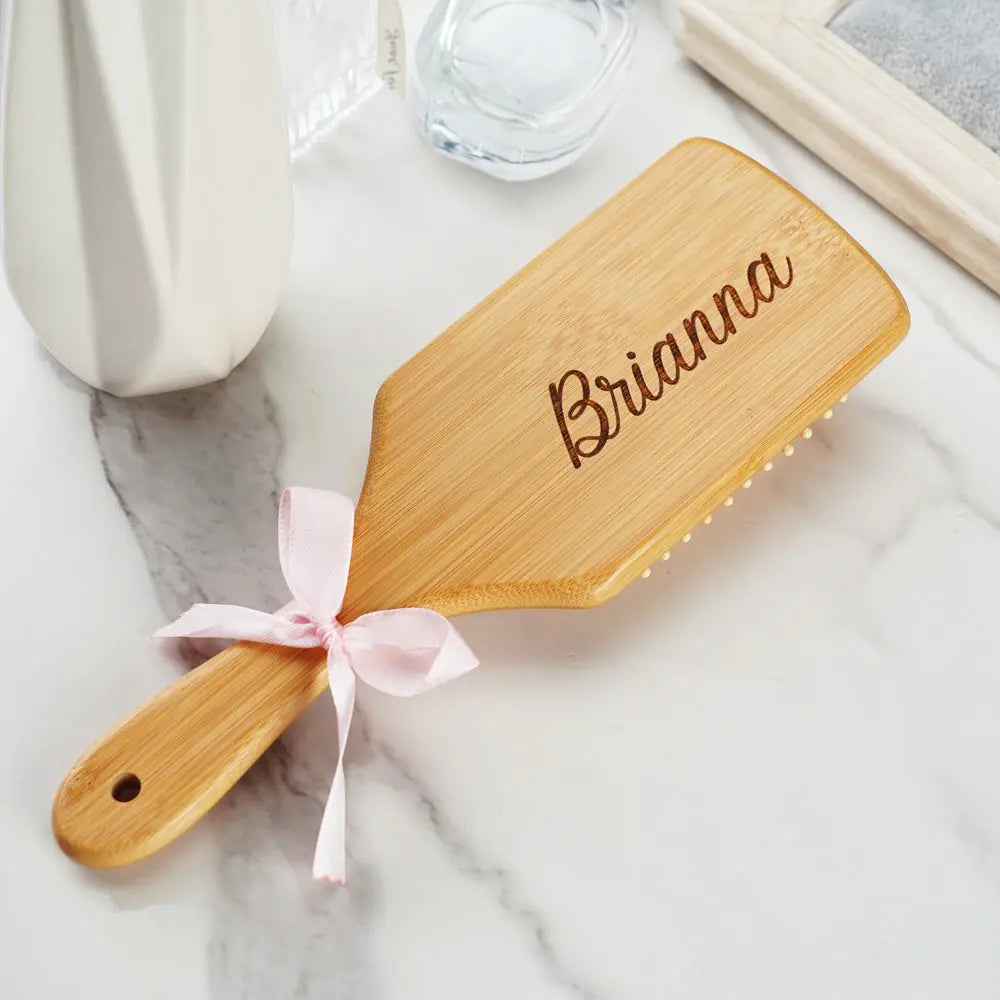 Hand holding a personalised bamboo hairbrush while detangling hair – gentle on scalp and a thoughtful bridesmaid gift