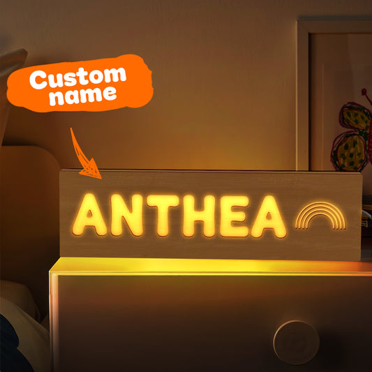 Personalised wooden night light with engraved name lit on a bedside, warm LED custom nursery night light and baby shower gift